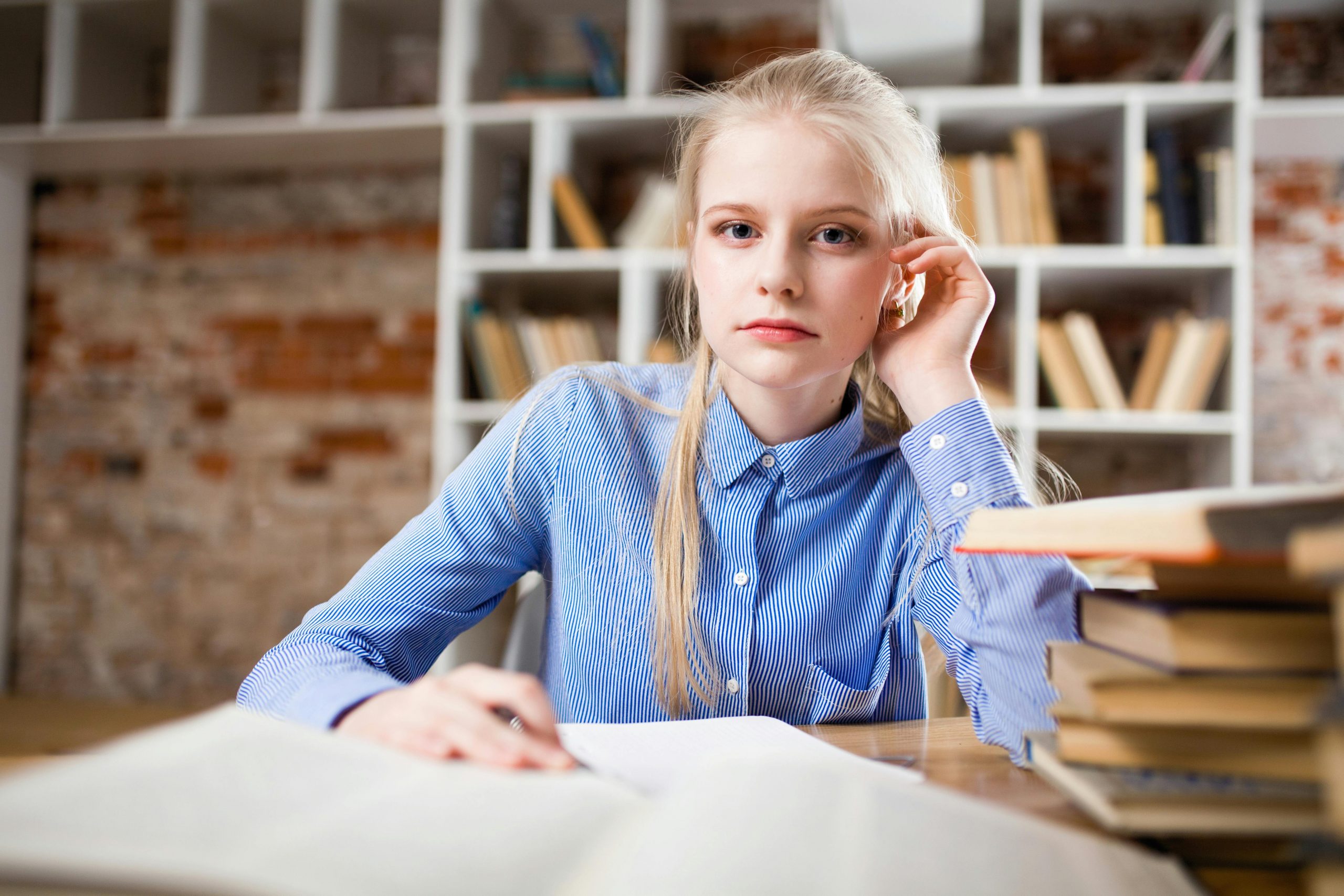 female student sitting at a desk full of books