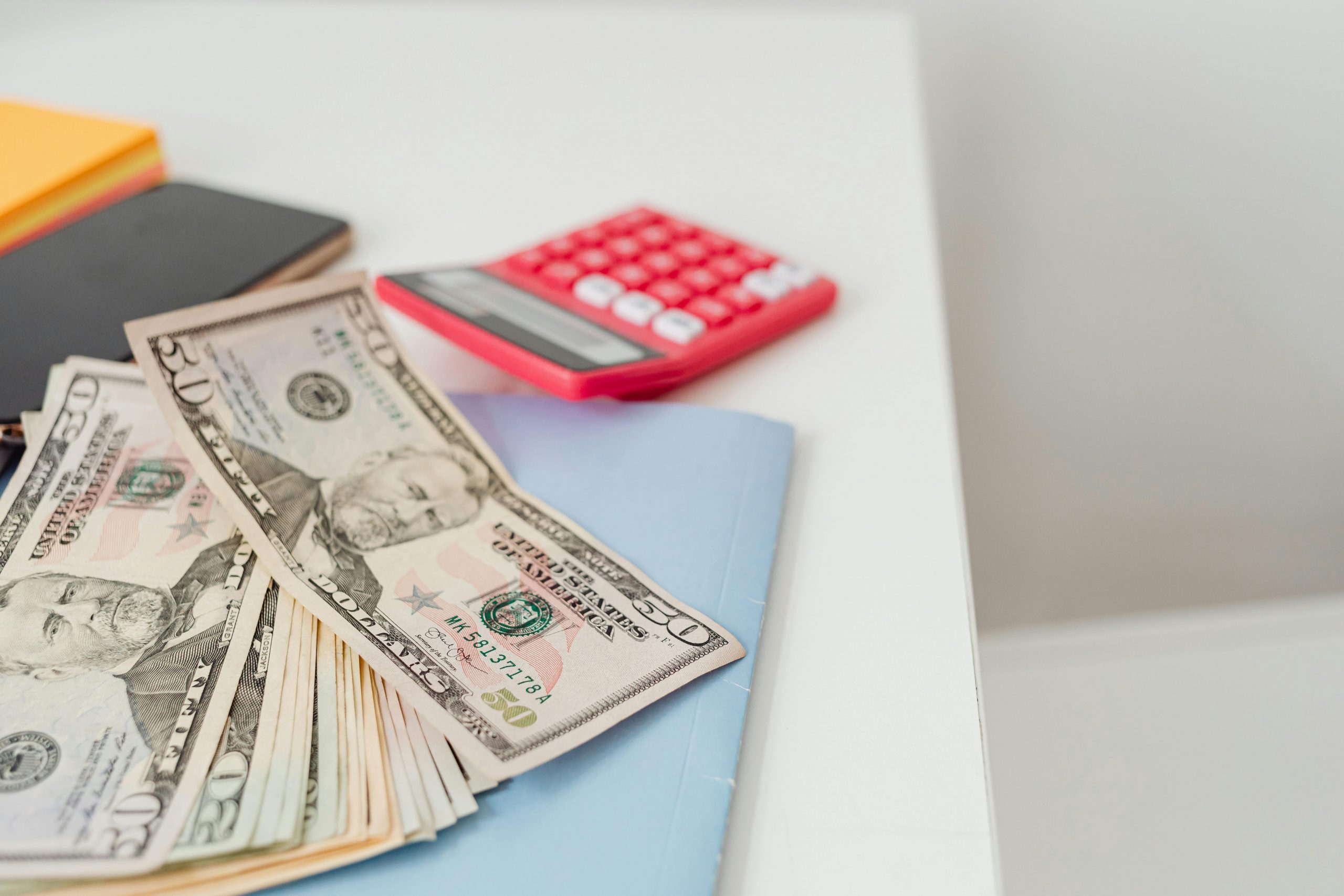 dollar bills and a red calculator on a desk