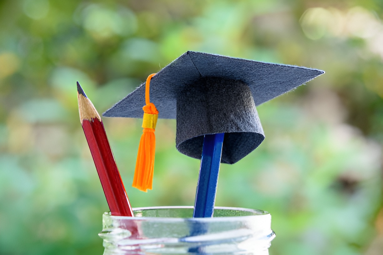 pencils and a miniature graduation cap in a jar